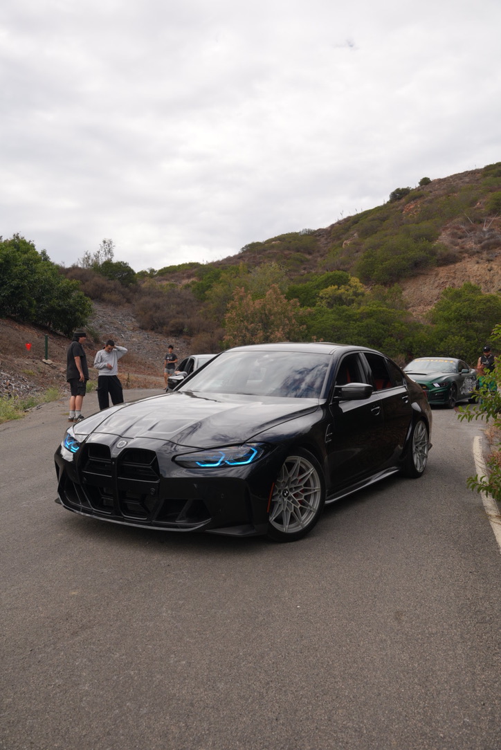 Brayden's dark gray BMW M3 on a coastal canyon road